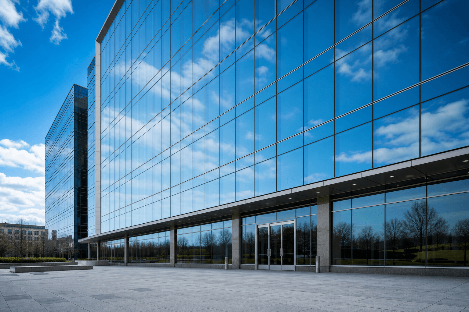 Low-angle wide view of modern commercial curtain wall and clean reflective glass; no people