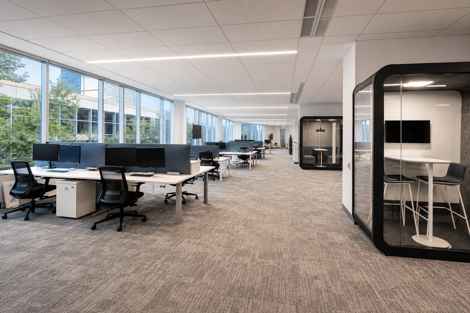Wide empty hybrid office floor with desks, monitors off, and collaboration tables; no people