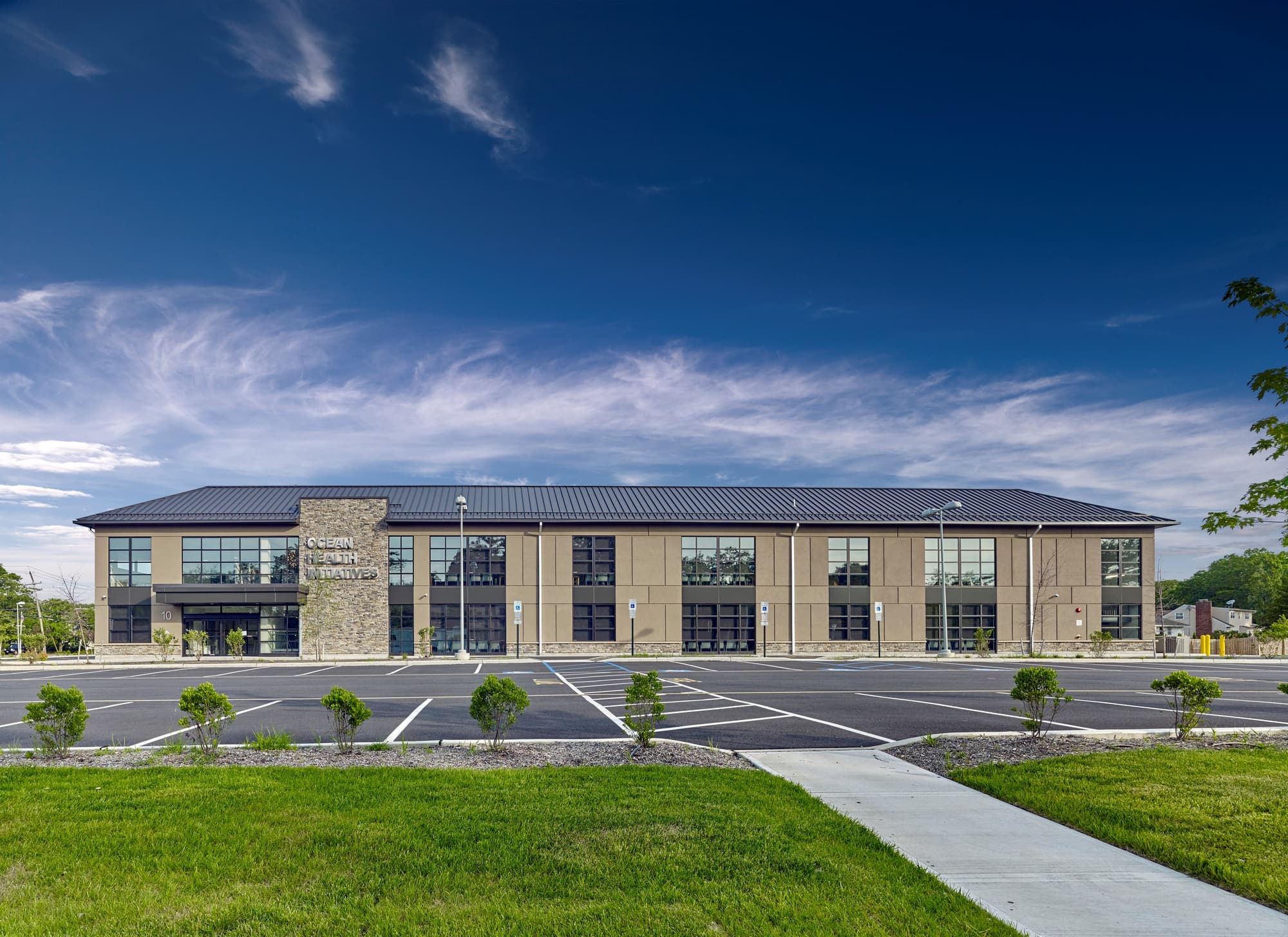 Exterior of the Ocean Health Initiatives community health center in Toms River, New Jersey — modern two-story medical office building with glass and stone facade